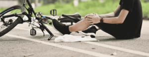 injured bicyclist holding their knee after falling off their bicycle
