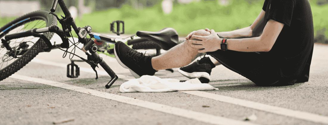 injured bicyclist holding their knee after falling off their bicycle
