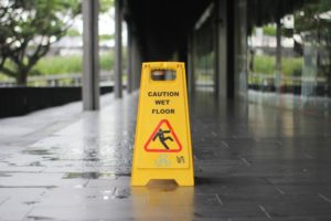 Photo of a caution wet floor sign placed right over a wet area on tile flooring.