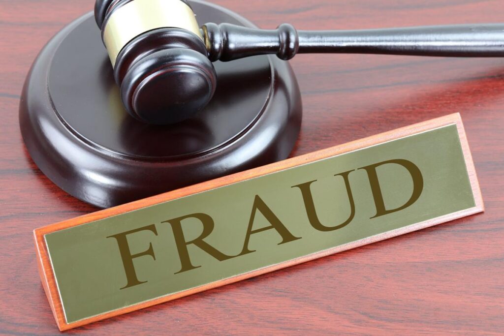 Gavel next to name plate with the word "fraud" engraved on it.