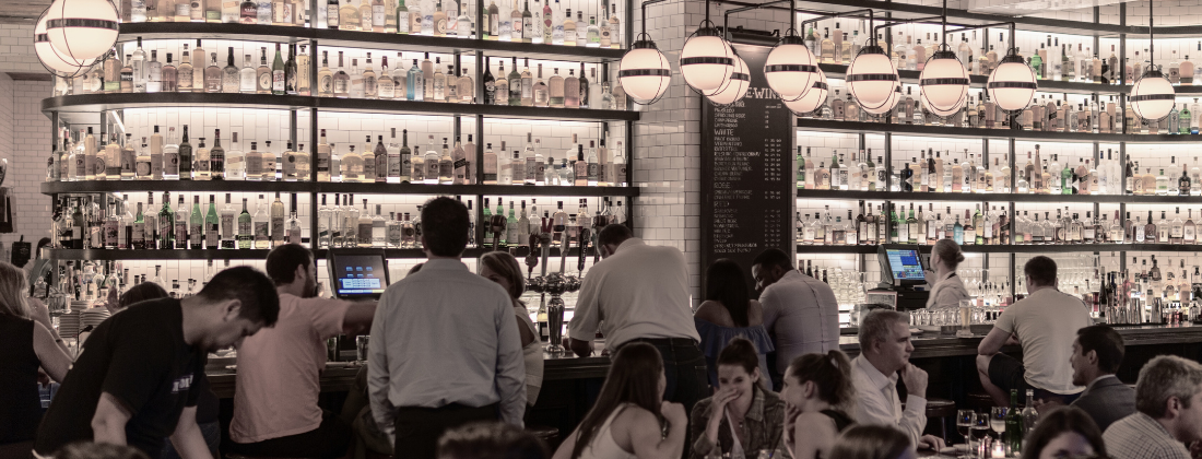 Photograph of a busy bar with patrons at the bar