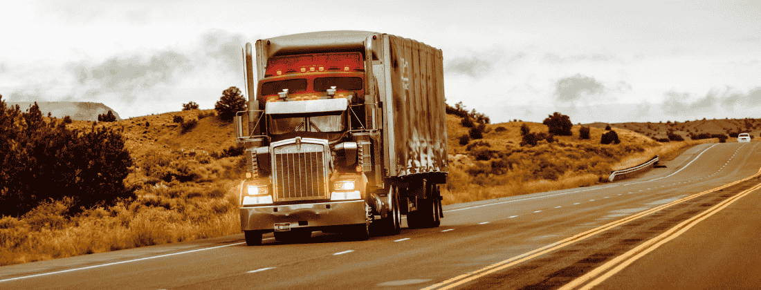 Photo of a big rig on a highway and a car at a distance.