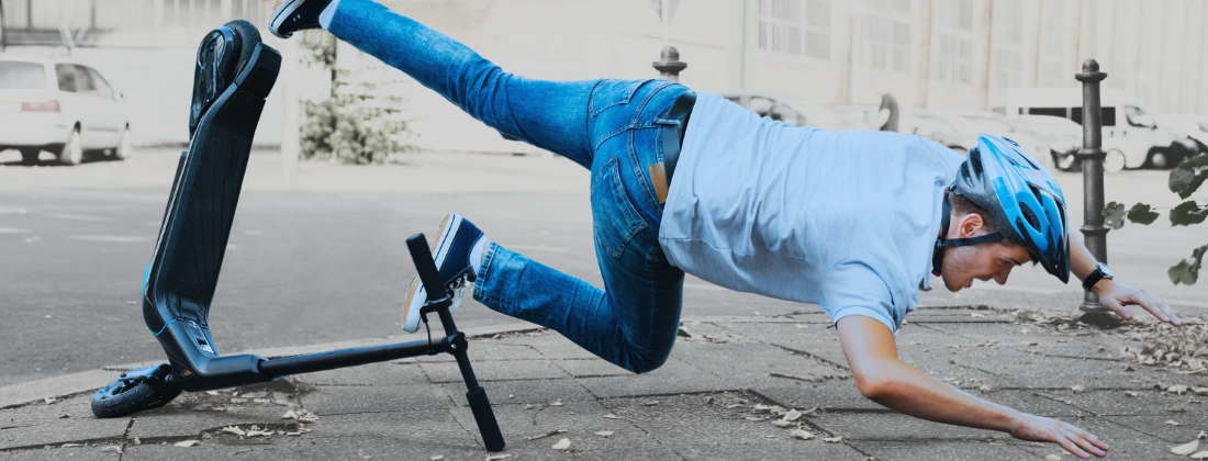 male falling of an electric scooter while wearing a helmet