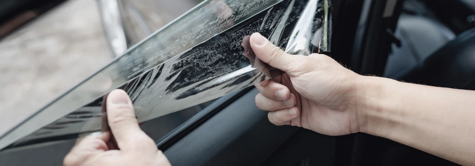 individual taking off window tint from vehicle