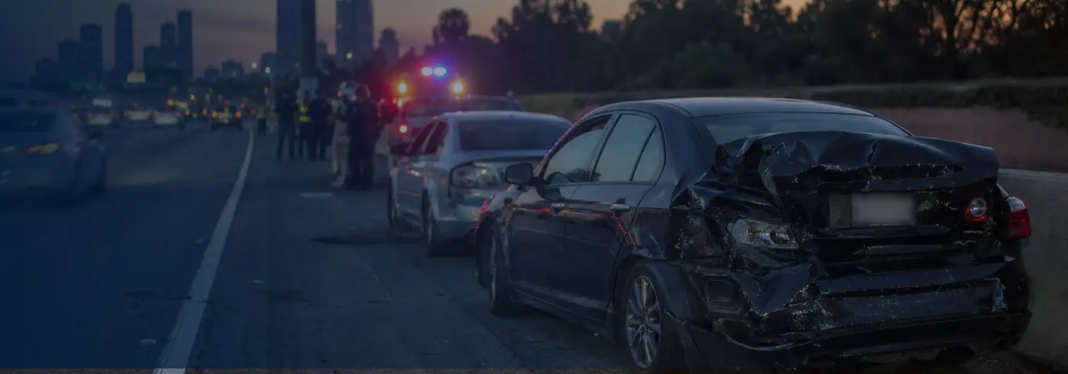 Car wreck on Los Angeles freeway with emergency vehicles at dusk