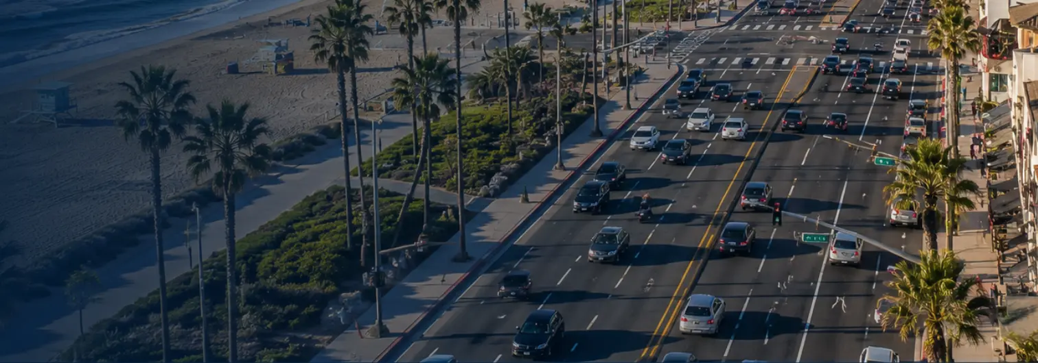 Aerial view of Pacific Coast Highway through Huntington Beach with multiple lanes of traffic and the coastline visible