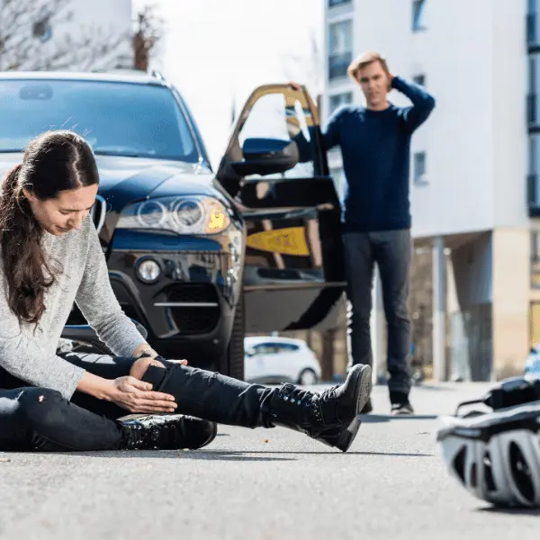 Electric bicycle rider down on the road with injury to her knee.