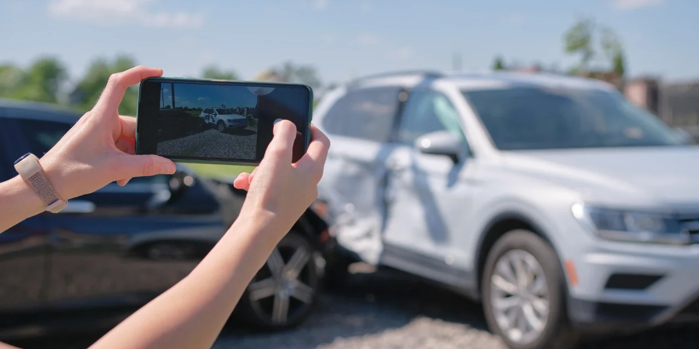 person holding a phone taking photos of the car accident